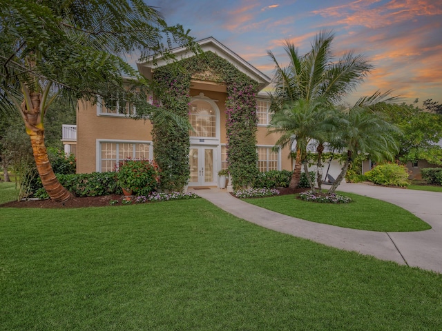 view of front facade with a lawn and french doors