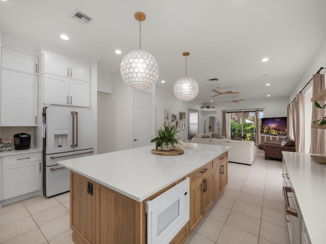 kitchen with a kitchen island, pendant lighting, white cabinetry, light tile patterned floors, and white appliances