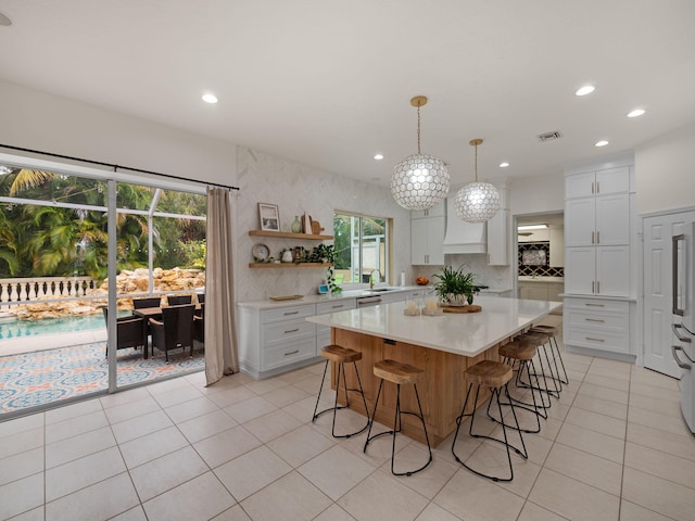 kitchen with a breakfast bar area, light tile patterned floors, a kitchen island, and white cabinets