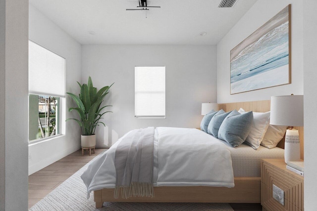 bedroom with visible vents, baseboards, and wood finished floors
