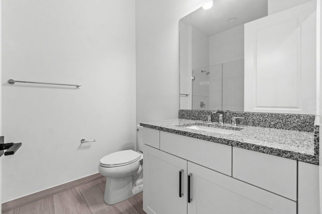 bathroom featuring vanity, toilet, wood-type flooring, and a shower