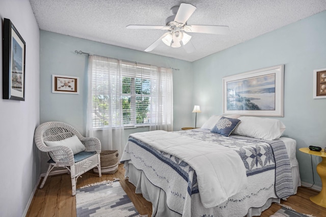 bedroom featuring ceiling fan, wood-type flooring, and a textured ceiling