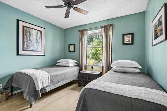 bedroom featuring ceiling fan, light hardwood / wood-style flooring, and a textured ceiling