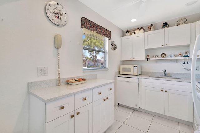 kitchen with sink, white appliances, light tile patterned floors, light stone countertops, and white cabinets