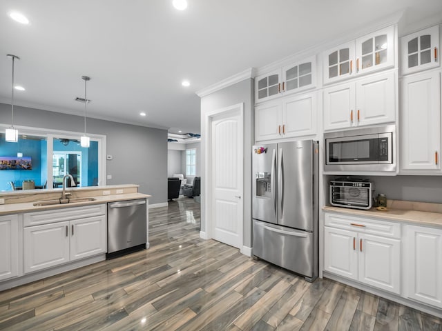 kitchen featuring pendant lighting, sink, crown molding, white cabinetry, and stainless steel appliances