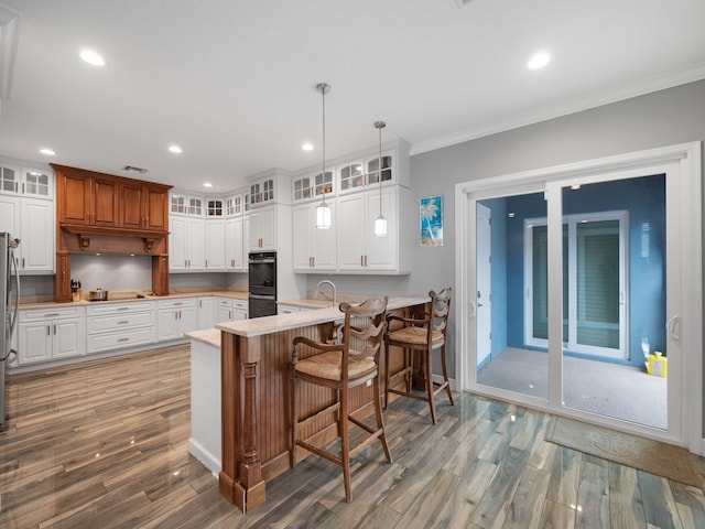 kitchen with white cabinetry, hanging light fixtures, a kitchen breakfast bar, kitchen peninsula, and black appliances