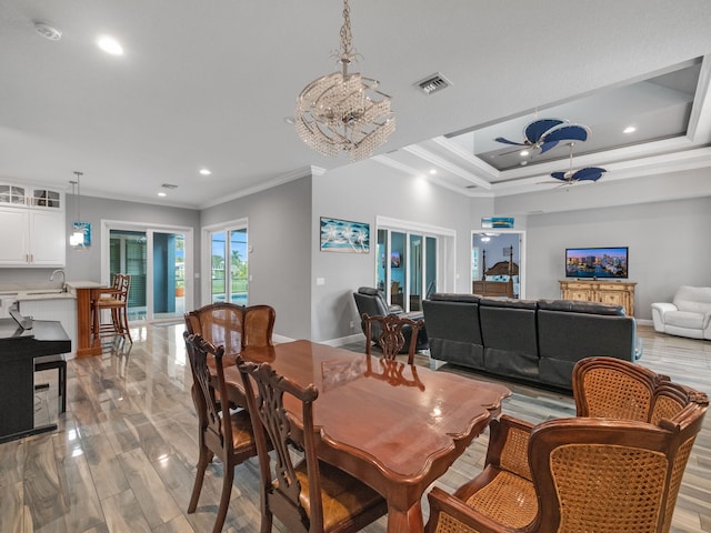 dining area with ornamental molding, a raised ceiling, and light wood-type flooring