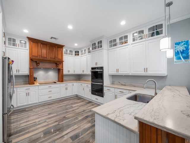 kitchen with sink, white cabinetry, light stone countertops, decorative light fixtures, and kitchen peninsula