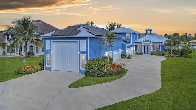 view of front facade featuring a garage, a lawn, and solar panels