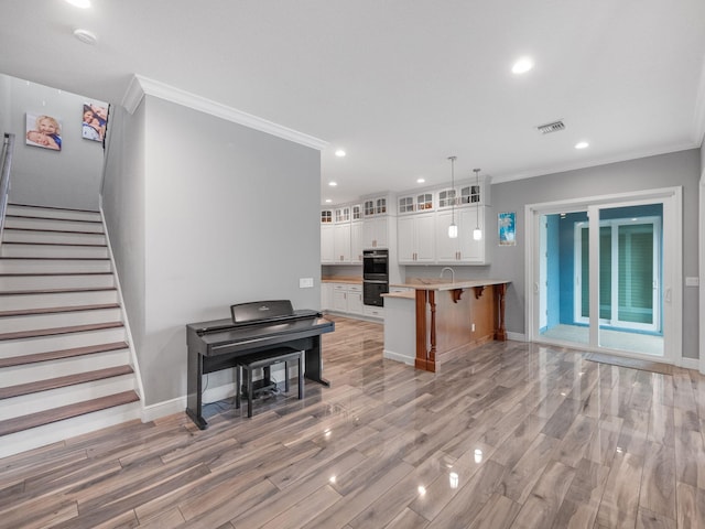 kitchen with white cabinetry, a kitchen breakfast bar, black double oven, kitchen peninsula, and light wood-type flooring