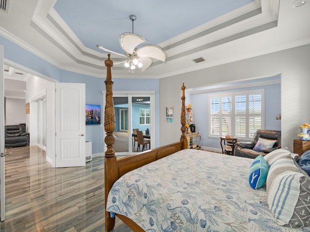 bedroom with a raised ceiling, ornamental molding, and hardwood / wood-style flooring