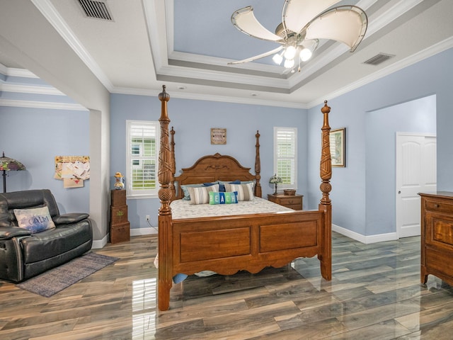 bedroom with crown molding, dark wood-type flooring, and a tray ceiling