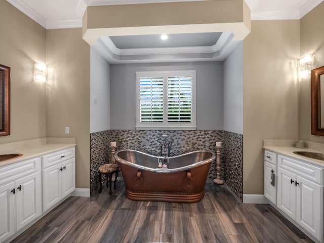 bathroom with a tub to relax in, crown molding, wood-type flooring, vanity, and a tray ceiling