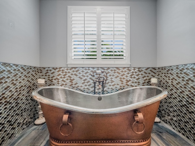 bathroom featuring hardwood / wood-style flooring, a bathing tub, and tile walls