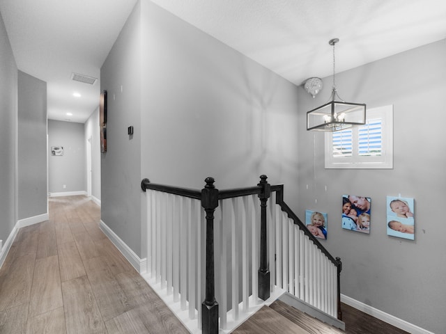 stairs with hardwood / wood-style floors and a notable chandelier