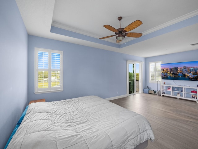 bedroom with hardwood / wood-style flooring, crown molding, access to outside, and a tray ceiling