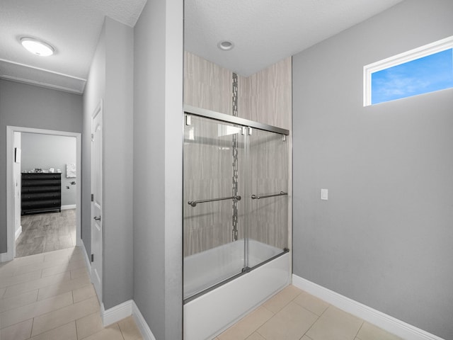 bathroom featuring bath / shower combo with glass door, tile patterned floors, and a textured ceiling