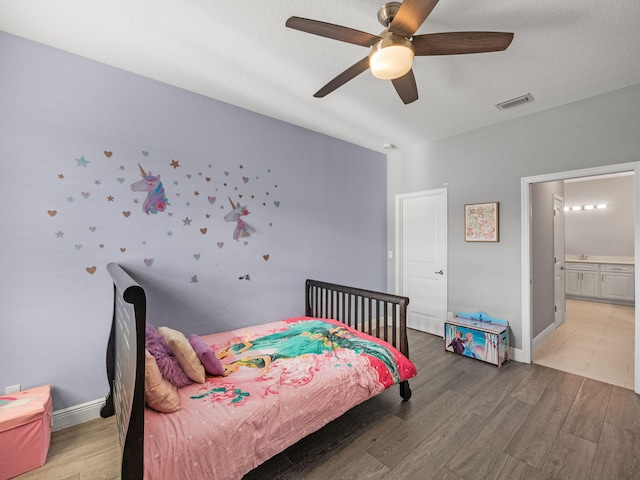 bedroom with ceiling fan, hardwood / wood-style floors, ensuite bathroom, and a textured ceiling