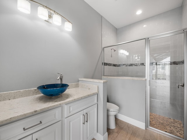 bathroom with vanity, toilet, an enclosed shower, and hardwood / wood-style floors