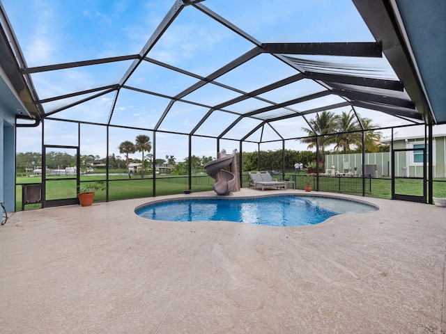 view of swimming pool with a patio, a water slide, glass enclosure, and a lawn