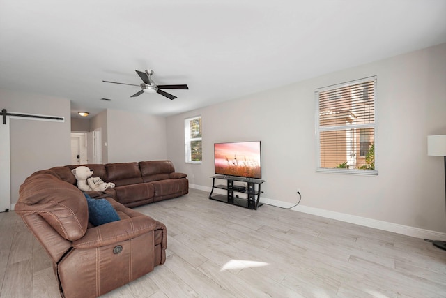 living room featuring a barn door, light wood-type flooring, and ceiling fan