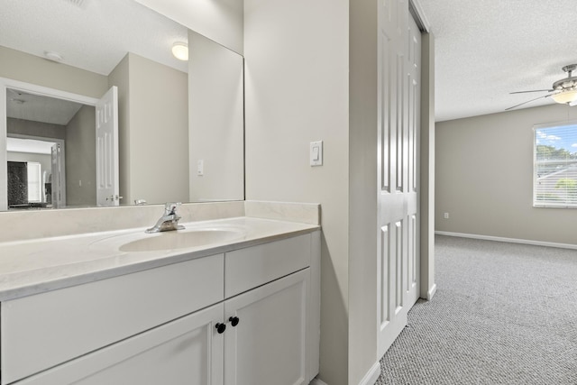 bathroom with ceiling fan, vanity, and a textured ceiling