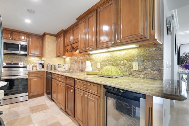 kitchen featuring light stone countertops, appliances with stainless steel finishes, sink, and beverage cooler