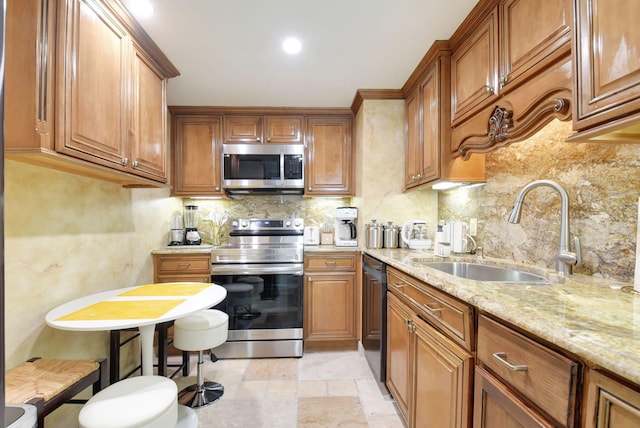 kitchen with sink, a breakfast bar, stainless steel appliances, tasteful backsplash, and light stone countertops