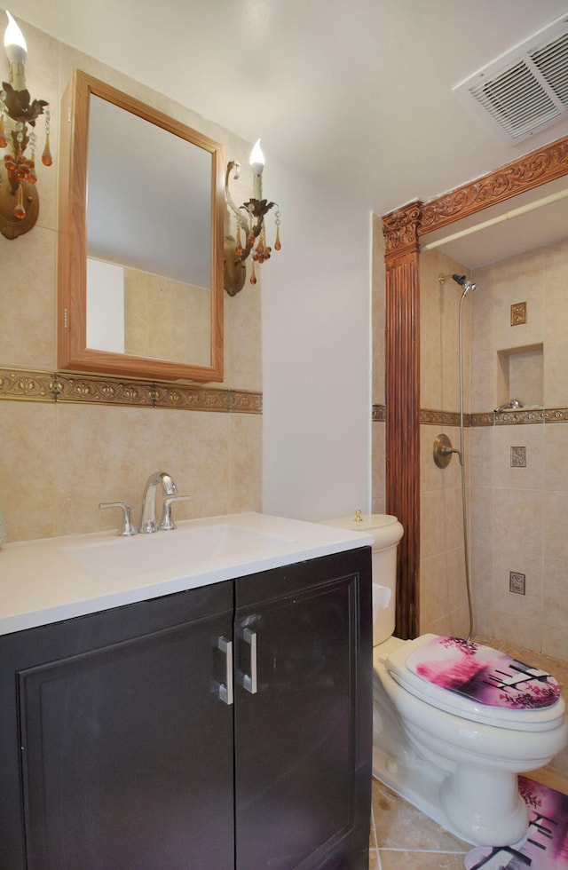 bathroom with a tile shower, backsplash, tile patterned flooring, vanity, and toilet