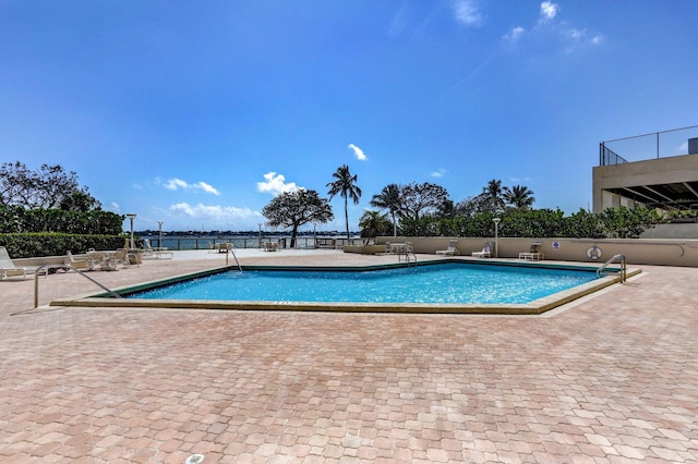 view of swimming pool featuring a water view and a patio area