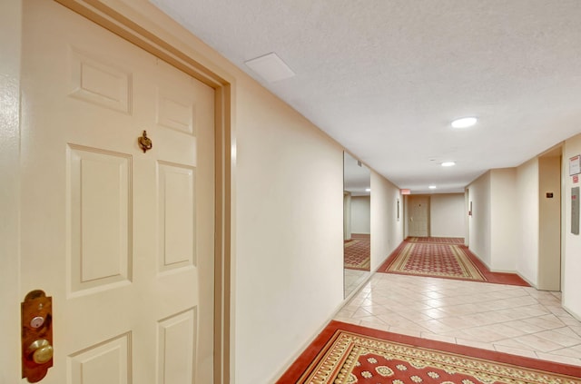 hall featuring light tile patterned floors and a textured ceiling