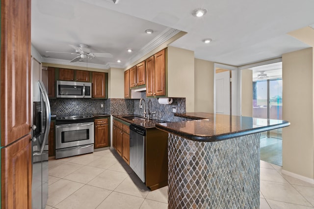 kitchen featuring sink, tasteful backsplash, dark stone countertops, appliances with stainless steel finishes, and kitchen peninsula