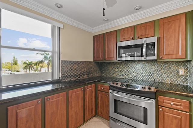 kitchen with tasteful backsplash, crown molding, dark stone counters, light tile patterned floors, and stainless steel appliances