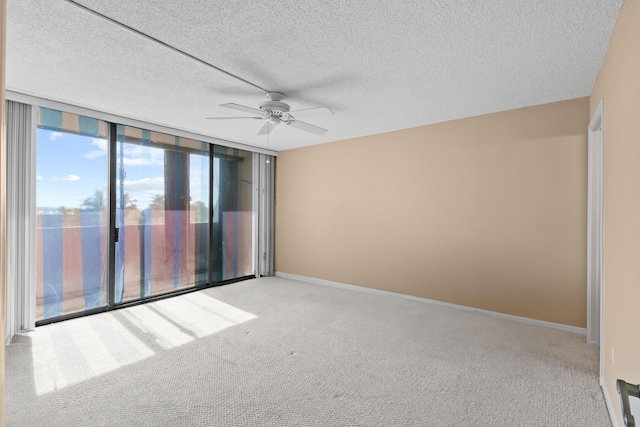 unfurnished room featuring light carpet, ceiling fan, a wall of windows, and a textured ceiling