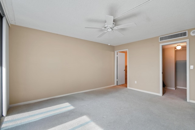 unfurnished bedroom with light carpet, ceiling fan, and a textured ceiling