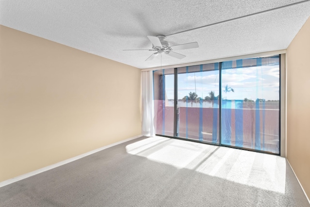 unfurnished room featuring ceiling fan, carpet floors, a textured ceiling, and a wall of windows