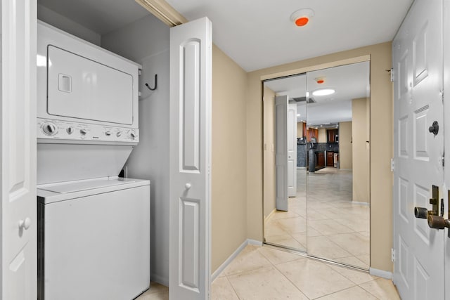 laundry room featuring stacked washing maching and dryer and light tile patterned floors