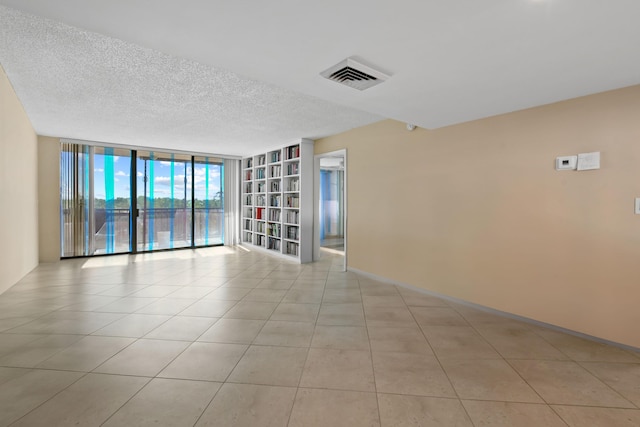 tiled spare room with expansive windows and a textured ceiling