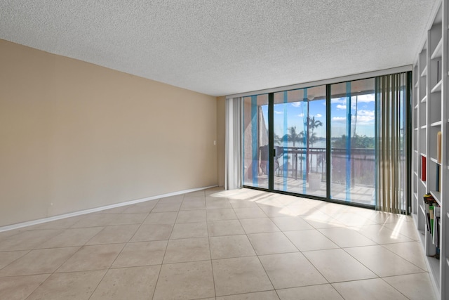 tiled spare room featuring floor to ceiling windows and a textured ceiling