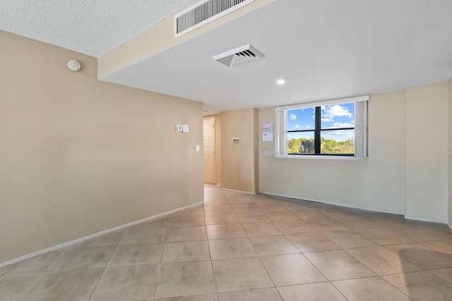 tiled empty room with a textured ceiling