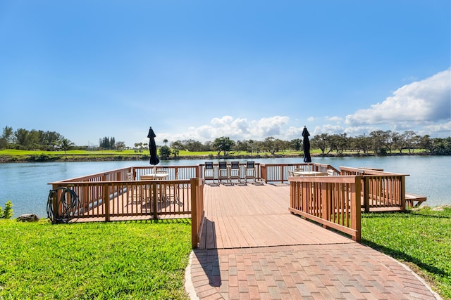 view of dock with a water view and a lawn