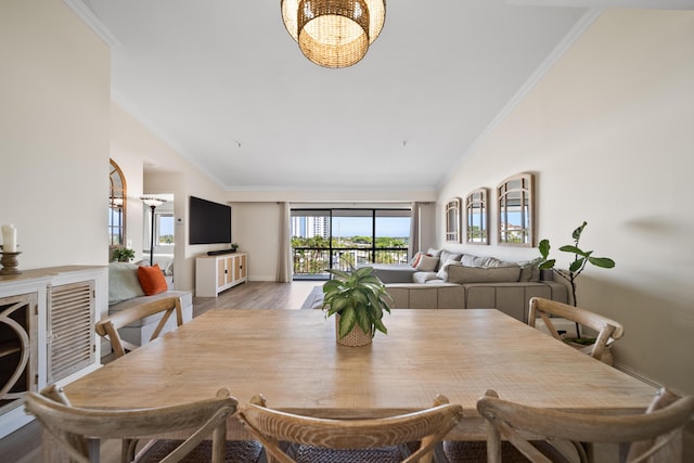 dining room with ornamental molding, high vaulted ceiling, and light hardwood / wood-style flooring