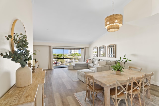 dining room featuring crown molding, high vaulted ceiling, and light hardwood / wood-style flooring