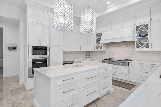 kitchen featuring white cabinetry, decorative light fixtures, stainless steel appliances, and premium range hood