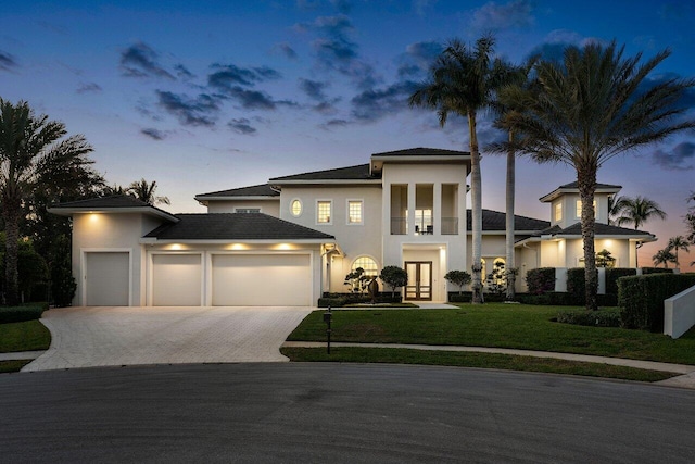 view of front of home with a yard, a garage, french doors, and a balcony