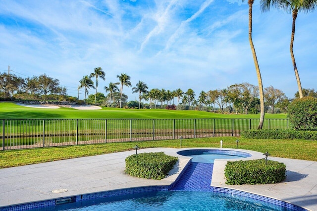 view of swimming pool featuring a lawn and an in ground hot tub