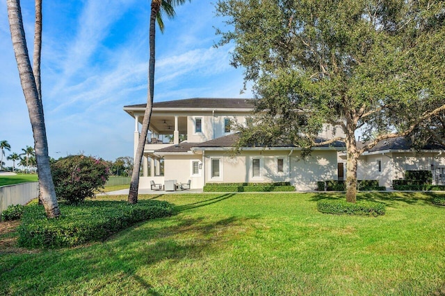 back of property with a balcony, a patio, and a lawn