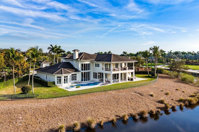 rear view of house featuring a water view, a balcony, a yard, and a patio area