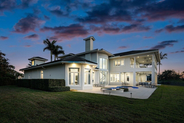 back house at dusk featuring a fenced in pool, a patio area, a balcony, and ceiling fan