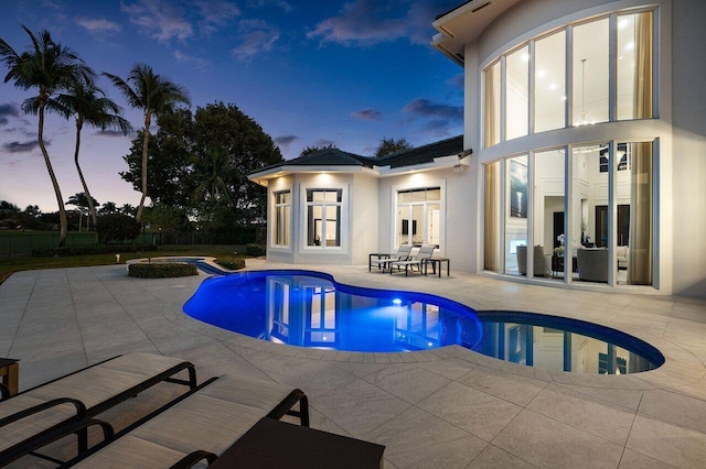 pool at dusk featuring a patio